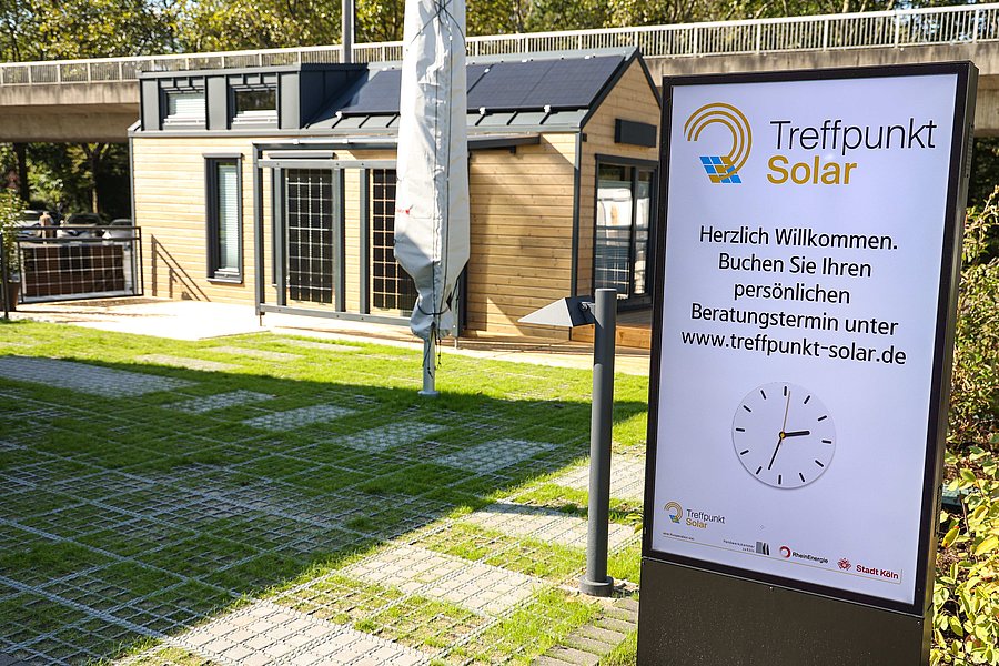 Vor dem Treffpunkt Solar steht ein Plakat mit dem Text: Herzlich Willkommen. Buchen Sie Ihren persönlichen Beratungstermin unter www.treffpunkt-solar.de