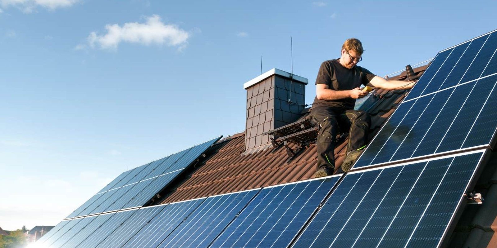 Mann montiert Solaranlage auf Dach
